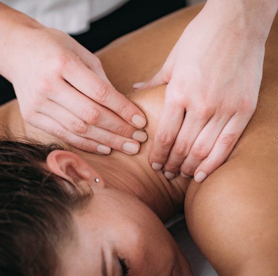 Shoulder blade Sports Massage Therapy Physiotherapist massaging female patient with injured shoulder blade. Sports injury treatment.